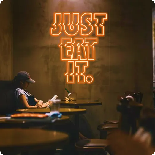 Letrero neón con la frase Just Eat It en interior de restaurante